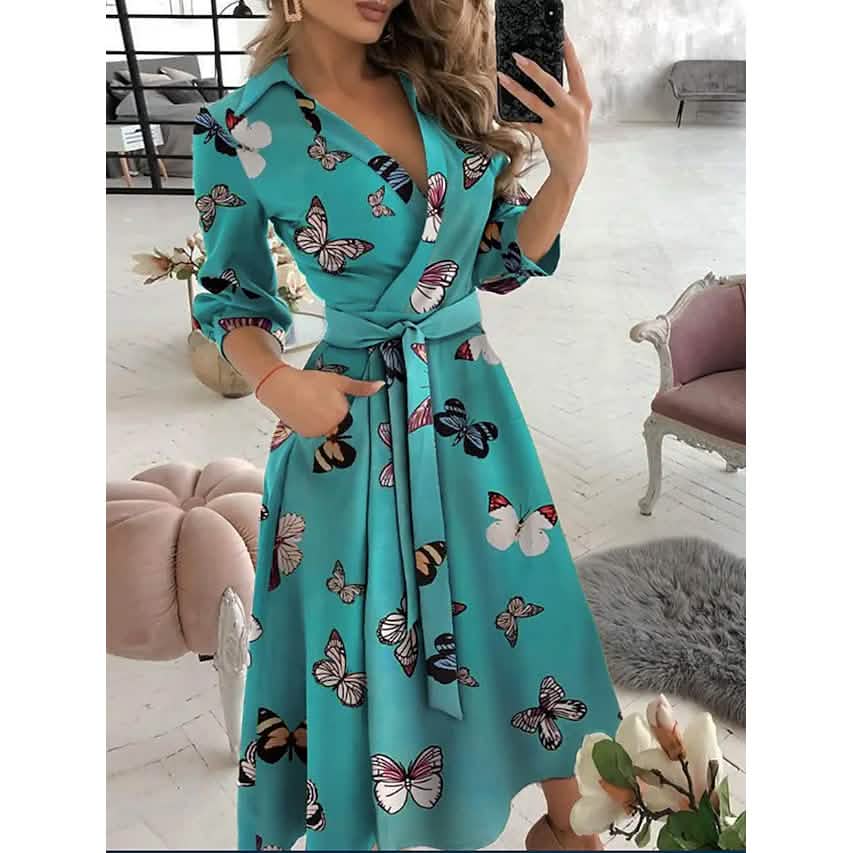 Woman wearing a turquoise dress with butterfly pattern in an indoor setting.